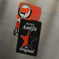Schwarzer Aufkleber mit Aufschrift "libertäre Antifa das Original" und einem rot / schwarzen Stern Schwarzer Aufkleber mit Aufschrift "libertäre Antifa das Original" und einem rot / schwarzen Stern