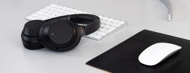 Graue Tastatur und graue Maus zusammen mit einem schwarzen Kopfhörer.