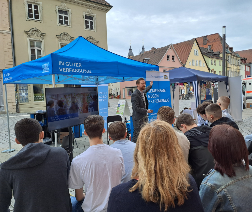 Blauer Infostand der BIGE in der Stadt Bayreuth mit Pavillon, Referenten und Passanten