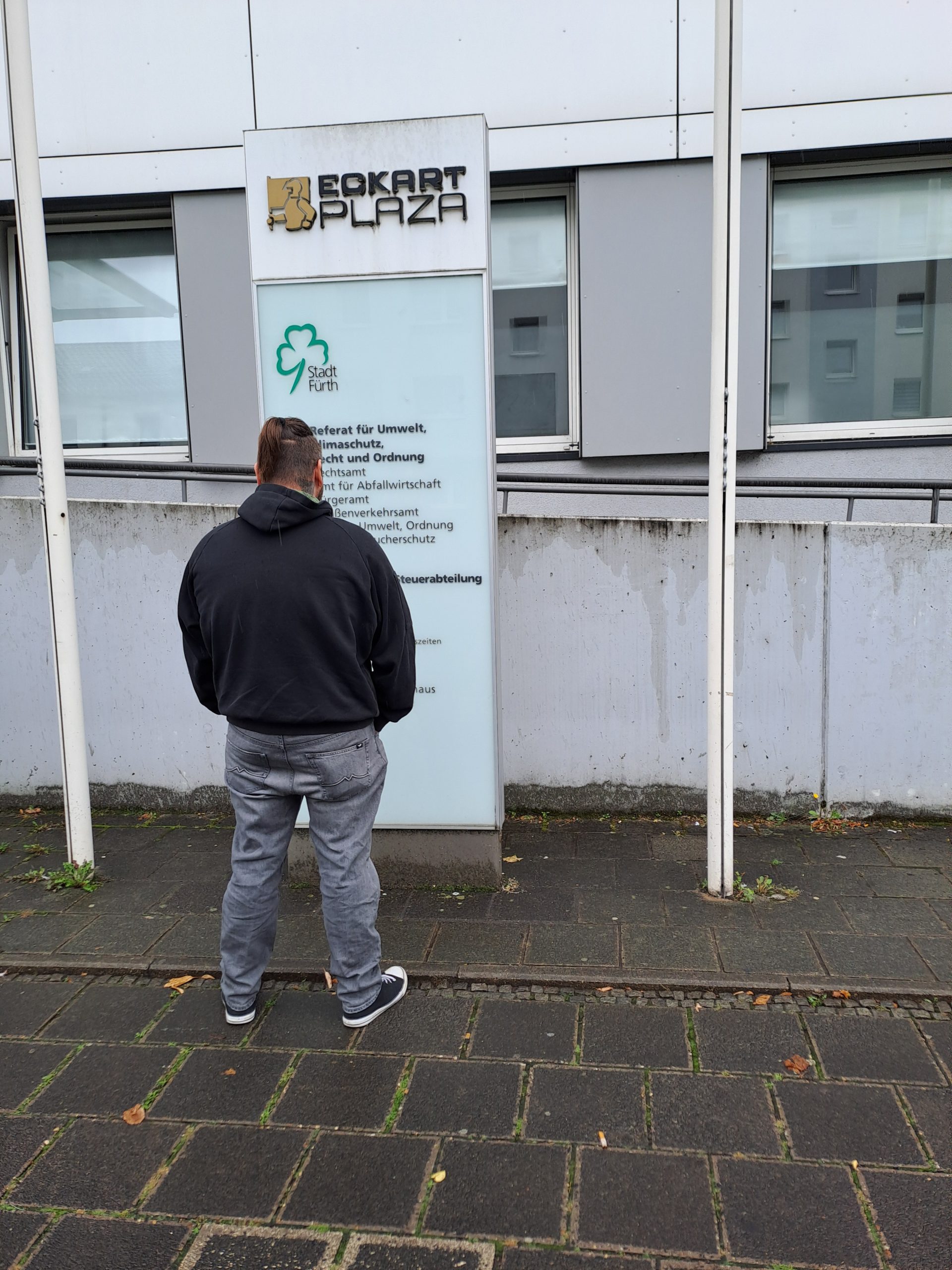 Männliche Person vor einem Gebäude und davor befindlichem Schild der Stadt Fürth stehend