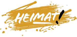 Symbol Logo Partei Die Heimat, weißer Schriftzug Heimat mit schwarzem Ausrufezeichen auf schraffiertem gelbem Hintergrund