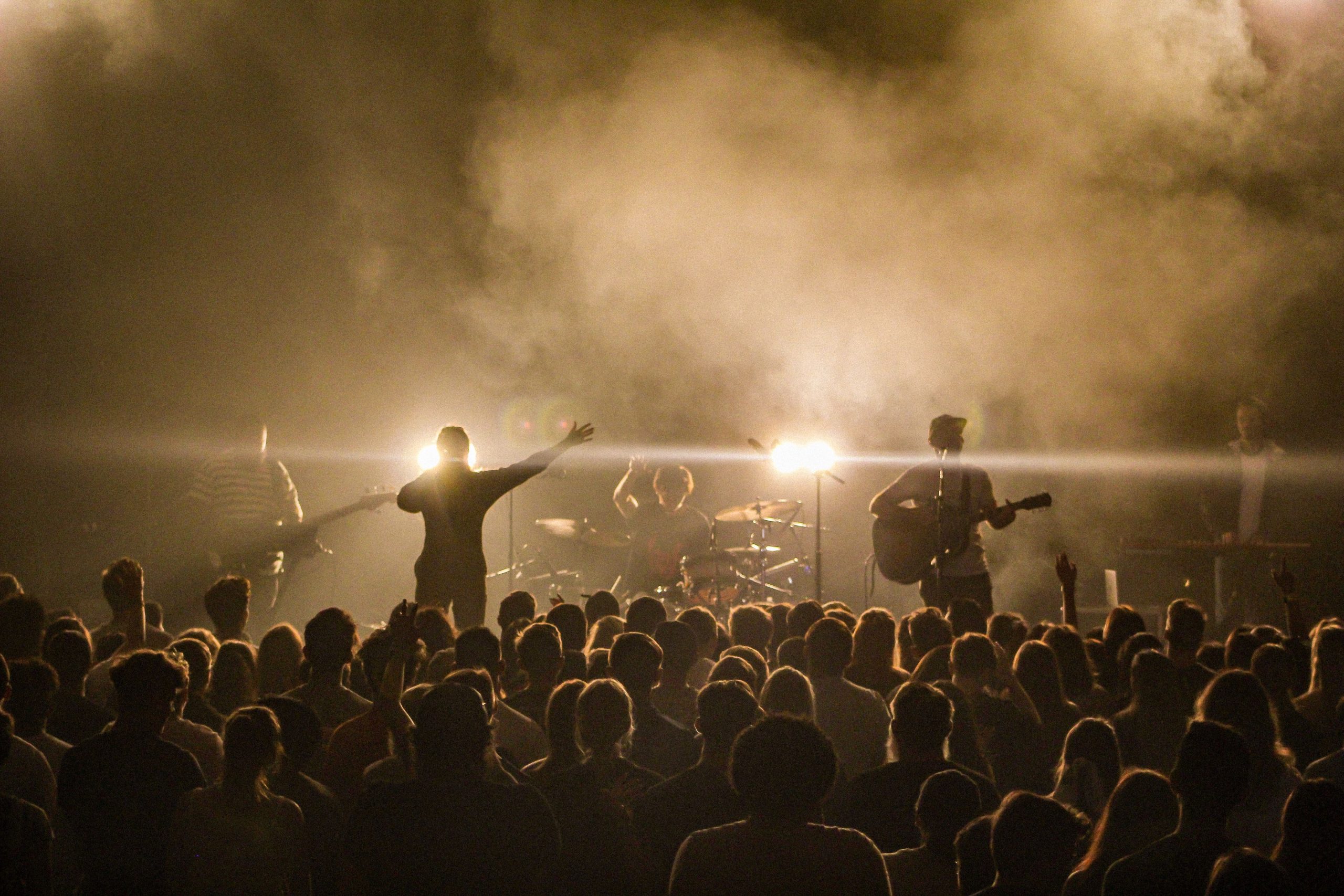 Musiker auf einer Bühne vor mehreren Zuschauer-Reihen.