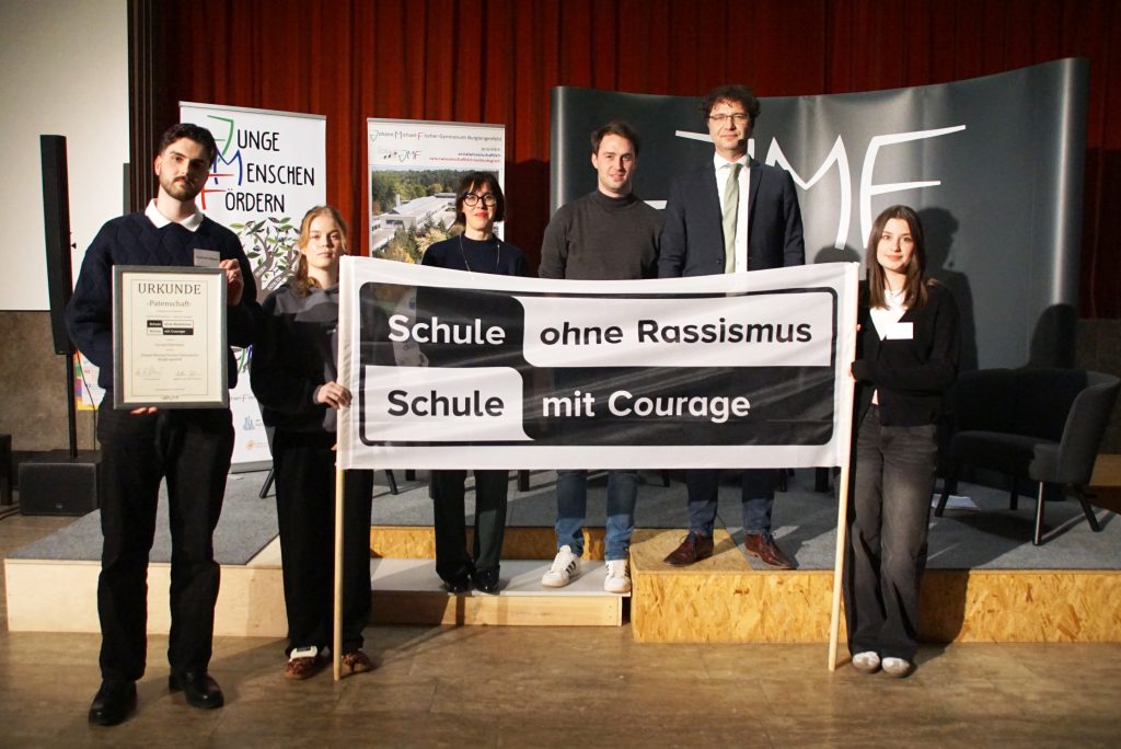 Schüler und Lehrer zeigen ein Plakat mit der Aufschrift "Schule ohne Rassismus/Schule mit Courage"